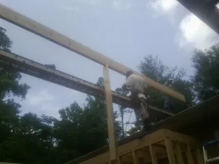 Carpenter setting a ridge beam over a new addition frame — Ice Dam Removal by Roofing Brothers in New Era