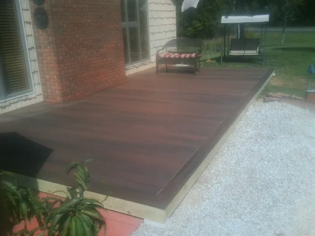 Freshly stained wood deck built against a brick home in New Era