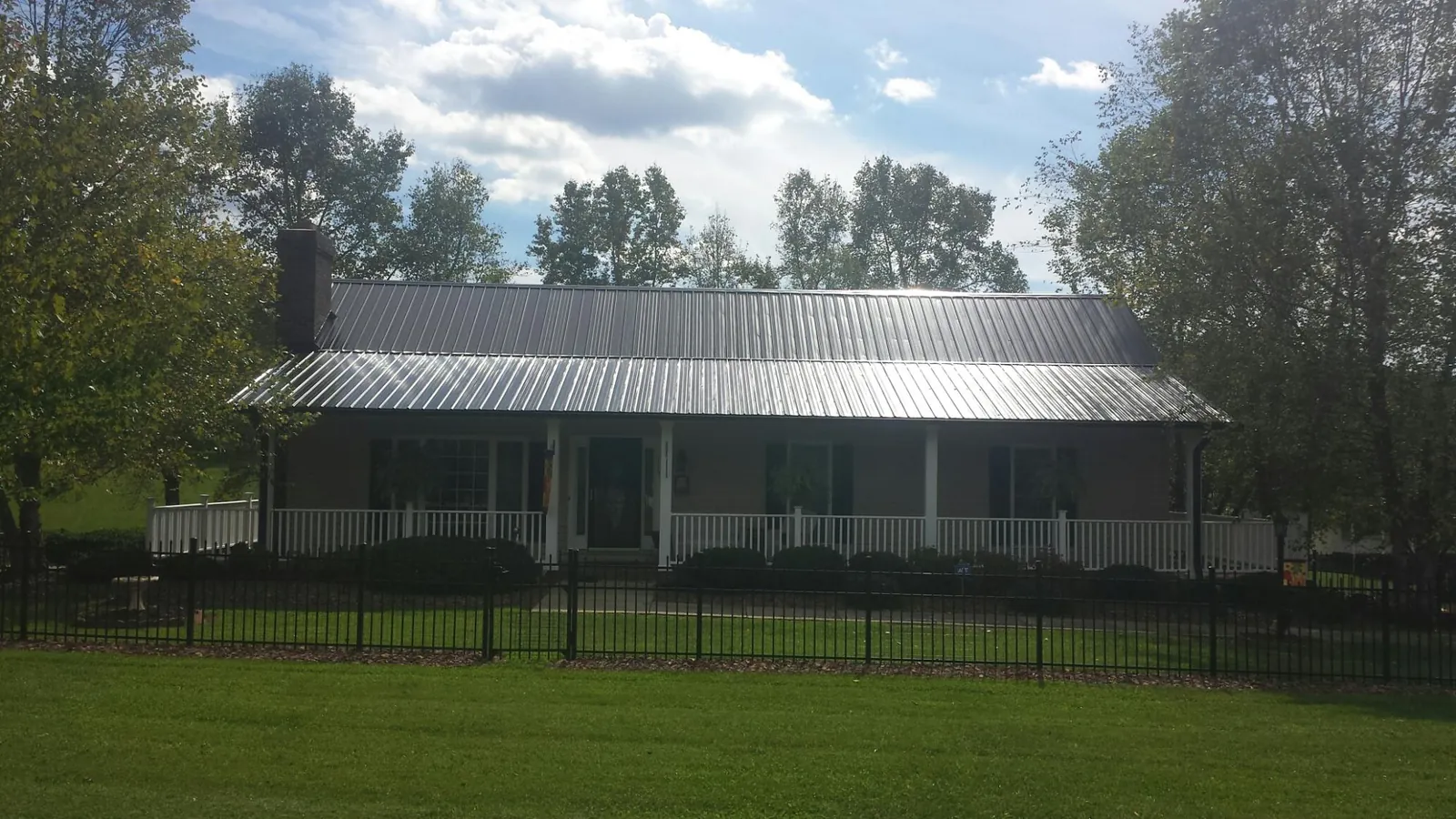 Gray metal roof on a brick ranch with a full width front porch — Gutter Guard Installation work by our crew in New Era