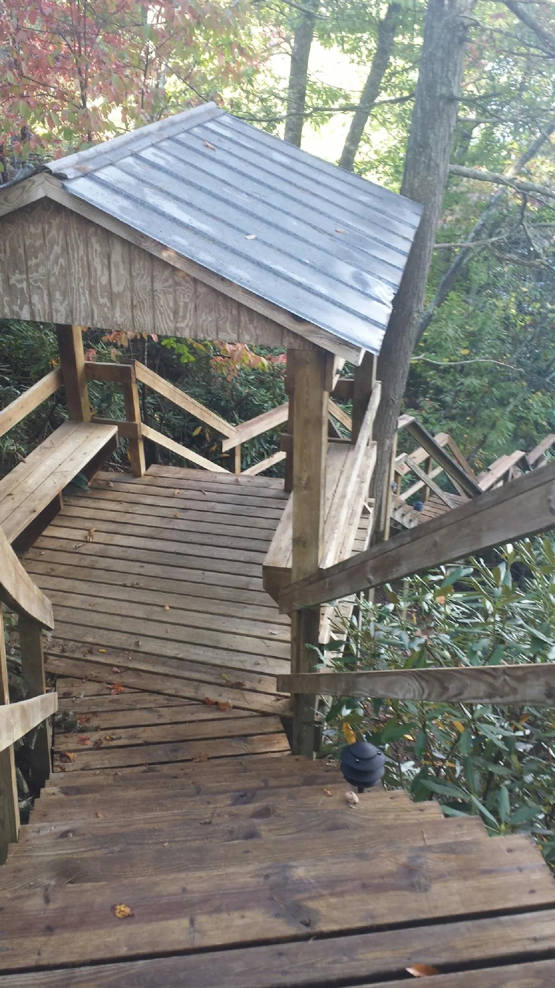 Metal roofed shelter over wooden steps on a wooded walkway — Skylight Repair & Installation work by our crew in New Era