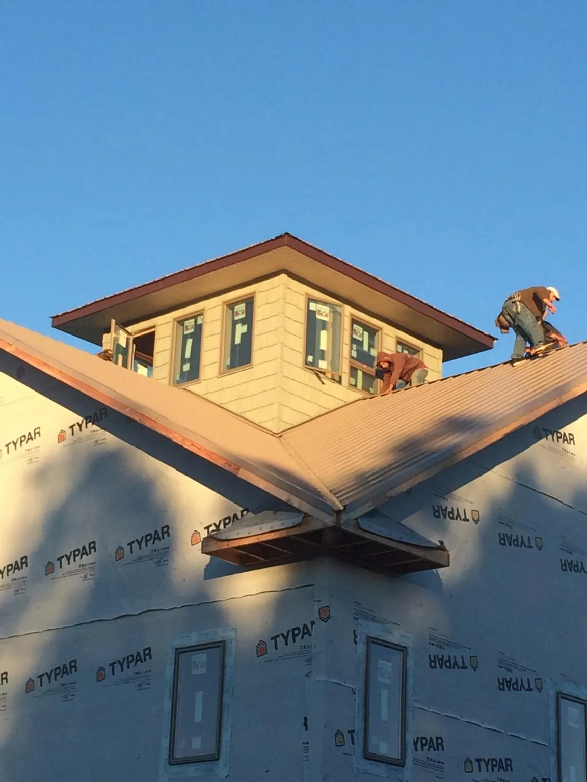 Roofers working around a rooftop cupola on a new metal roof at sunset — Roof Waterproofing in New Era by Roofing Brothers